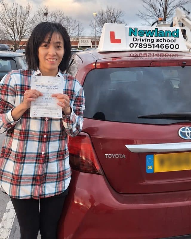 Pupil with her pass certificate beside the red Toyota Yaris